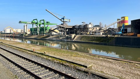 Ein Industriegebiet mit am Hafenbecken, verschiedenen Maschinen und einer Eisenbahnstrecke.