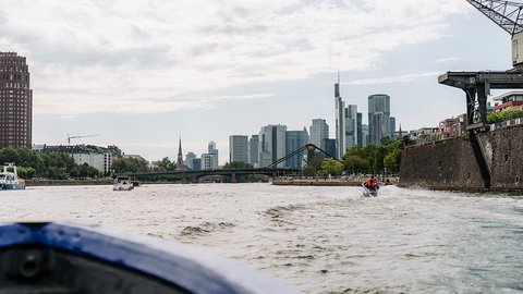 Der Osthafen mit Booten, einem Jetski und der Frankfurter Skyline im Hintergrund.